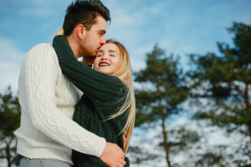 happy couple kissing and hugging in the park on a snowy winter day