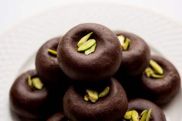 Chocolate Milk peda or pera or pedha made using sweet condensed Milk and cocoa powder, garnished with Pistachio. selective focus