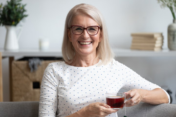 Head shot portrait smiling mature woman holding cup of tea