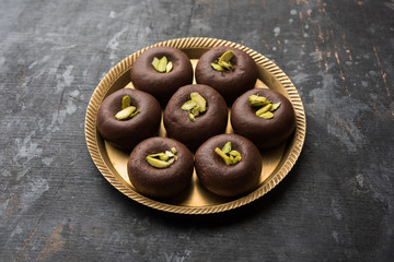 Chocolate Milk peda or pera or pedha made using sweet condensed Milk and cocoa powder, garnished with Pistachio. selective focus