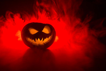 Fototapeta premium Halloweenowy uśmiech dyni i przerażające oczy na imprezową noc. Zamknij widok strasznej dyni Halloween z oczami świecącymi wewnątrz na czarnym tle