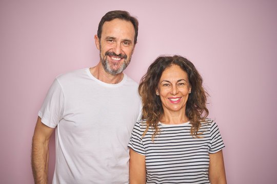 Beautiful middle age couple together standing over isolated pink background with a happy and cool smile on face. Lucky person.