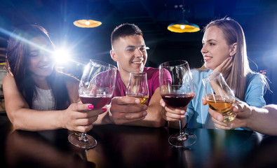 Cheerful friends in the pub. Drinking beer, wine and whisky, talking, having fun.