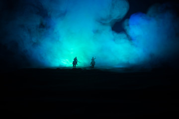 World war officer (or warrior) rider on horse with a sword ready to fight and soldiers on a dark foggy toned background. Battle scene battlefield of fighting soldiers.