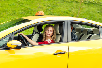 Photo of blonde female driver sitting in yellow taxi on summer