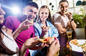 Cheerful friends in the pub. Drinking beer, eating pizza, talking, having fun.