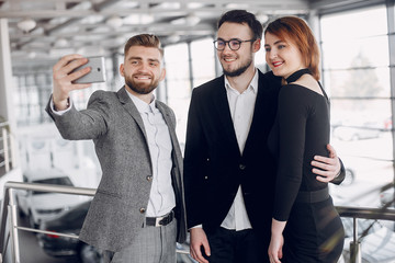 Couple in a car salon. Family buying the car. Elegant woman with her husband. Assistant with a clients