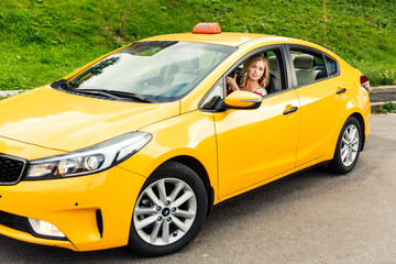 Plakat Photo of woman driver sitting in yellow taxi on summer.