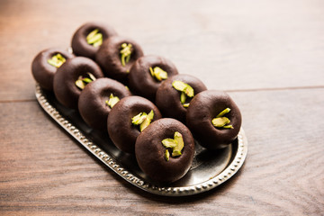 Chocolate Milk peda or pera or pedha made using sweet condensed Milk and cocoa powder, garnished with Pistachio. selective focus