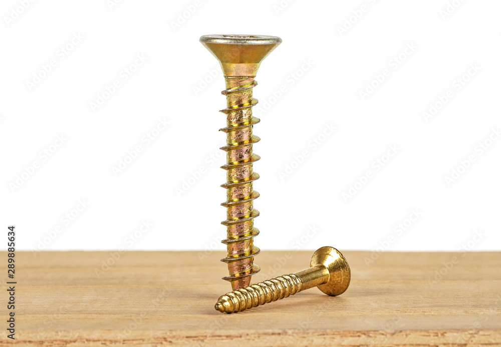 Poster industrial concept - two golden screws on wooden plank, white background. selective focus.