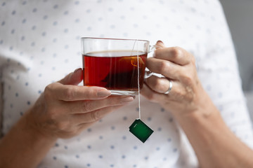 Close up older mature woman holding cup of black tea