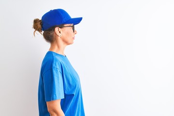 Senior deliverywoman wearing cap and glasses standing over isolated white background looking to side, relax profile pose with natural face with confident smile.