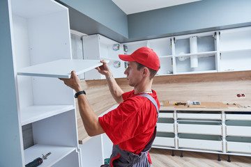 kitchen installation. Worker assembling furniture