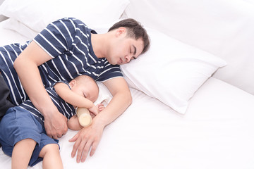 Young Asian father sleeping with little baby boy after tired taking care his son.