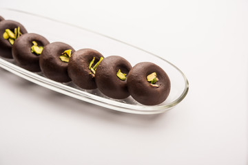 Chocolate Milk peda or pera or pedha made using sweet condensed Milk and cocoa powder, garnished with Pistachio. selective focus