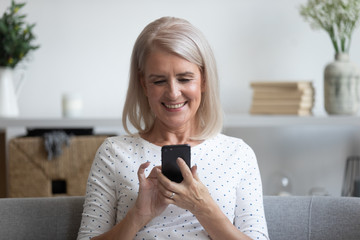 Smiling mature woman holding phone, using mobile device apps