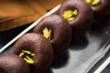 Chocolate Milk peda or pera or pedha made using sweet condensed Milk and cocoa powder, garnished with Pistachio. selective focus