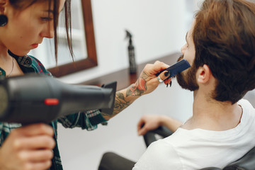 Man with a beard. Hairdresser with a client. Woman with a hair dryer