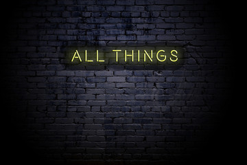 Highlighted brick wall with neon inscription all things