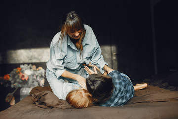 Beautiful mother with two daughter. Family sitting in the room on a bed.