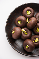 Chocolate Milk peda or pera or pedha made using sweet condensed Milk and cocoa powder, garnished with Pistachio. selective focus