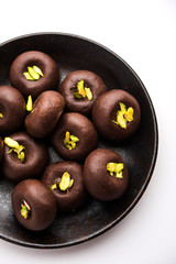 Chocolate Milk peda or pera or pedha made using sweet condensed Milk and cocoa powder, garnished with Pistachio. selective focus