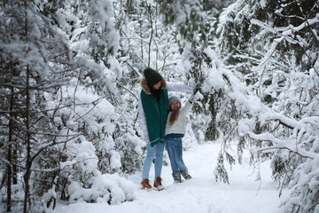 Young family for a walk. Mom and daughter are walking in a winter park.