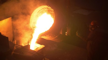 Industrial worker casting metal at metallurgical factory. Molding molten metal