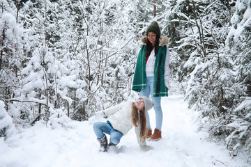 Young family for a walk. Mom and daughter are walking in a winter park.