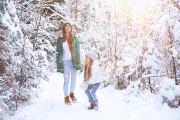 Young family for a walk. Mom and daughter are walking in a winter park.