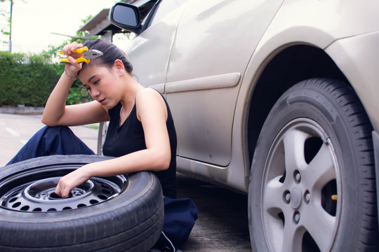 A woman is tired of changing tyre for automotive maintenance service
