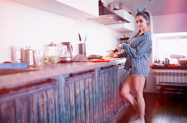 A cute young girl in the kitchen prepares food