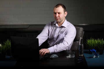 man sitting at table and working on laptop