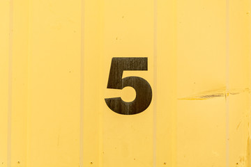 Number 5 stencilled in black on yellow background