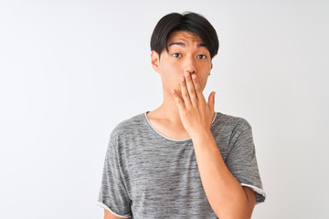 Young chinese man wearing casual t-shirt standing over isolated white background cover mouth with hand shocked with shame for mistake, expression of fear, scared in silence, secret concept