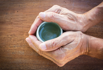 Man hands hold cup of tea on wood background. With dark vignette. Top view with copy space.