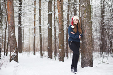 Fototapeta na wymiar A young girl in a winter park on a walk. Christmas holidays in the winter forest. The girl enjoys winter in the park.