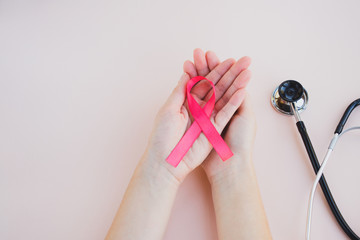 Womans hands hold pink breast cancer awareness ribbon on a light background. Medicine and...