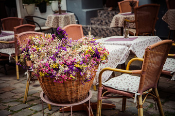 Fototapeta na wymiar Bucket with flowers in outdoor cafe in Lviv