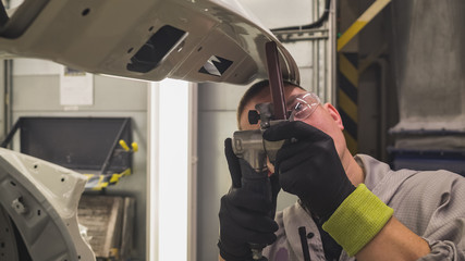 Works paint shop car body, the employee eliminates the defect with a special pneumatic tool