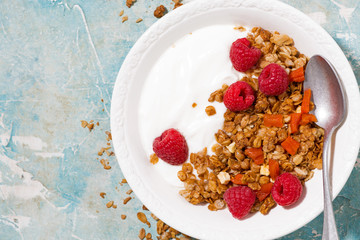 granola with dried apricots, fresh raspberries and yogurt for breakfast, closeup vertical