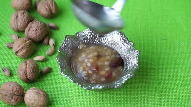 Preparation of Ashura dessert. Traditional  Turkish Dessert Noah Pudding, Ashura or Asure on the green surface with ingredients of dessert. Ashura day. 