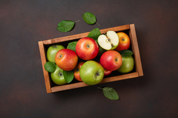 Ripe red and green apples in wooden box on a rusty background