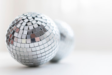 two disco balls on a light background with shadow