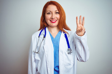 Young redhead doctor woman using stethoscope over white isolated background showing and pointing up with fingers number three while smiling confident and happy.