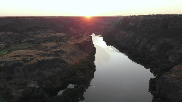 Aerial footage at sunrise of Snake River Canyon in Twin Falls, Idaho, USA. In the center background can be seen the I.B Perrine Bridge, a four lane truss arch bridge, on which the U.S Highway 93 runs