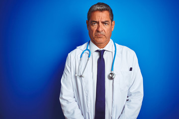Handsome middle age doctor man wearing stethoscope over isolated blue background skeptic and nervous, frowning upset because of problem. Negative person.