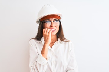 Young beautiful architect woman wearing helmet and glasses over isolated white background looking stressed and nervous with hands on mouth biting nails. Anxiety problem.