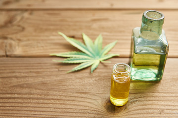 Hemp oil in a glass jar, hemp leaves on the background of wooden boards