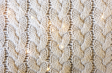 Pattern of warm winter autumn sweater close up, decorated with lights
